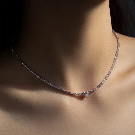 Necklace with a small diamond pendant on a person's neck against a dark background