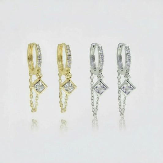 Pair of gold hoop earrings with diamond-like stones on a white background