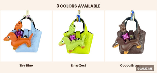 Three small handbag charms shown side by side in different colors under the heading '3 COLORS AVAILABLE': a light sky blue bag with an orange dachshund charm, a lime green bag with a green dachshund charm, and a dark cocoa brown bag with a brown dachshund charm. Each bag has a purple star-shaped accent.
