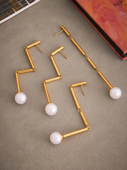 Gold and pearl earrings on a textured surface