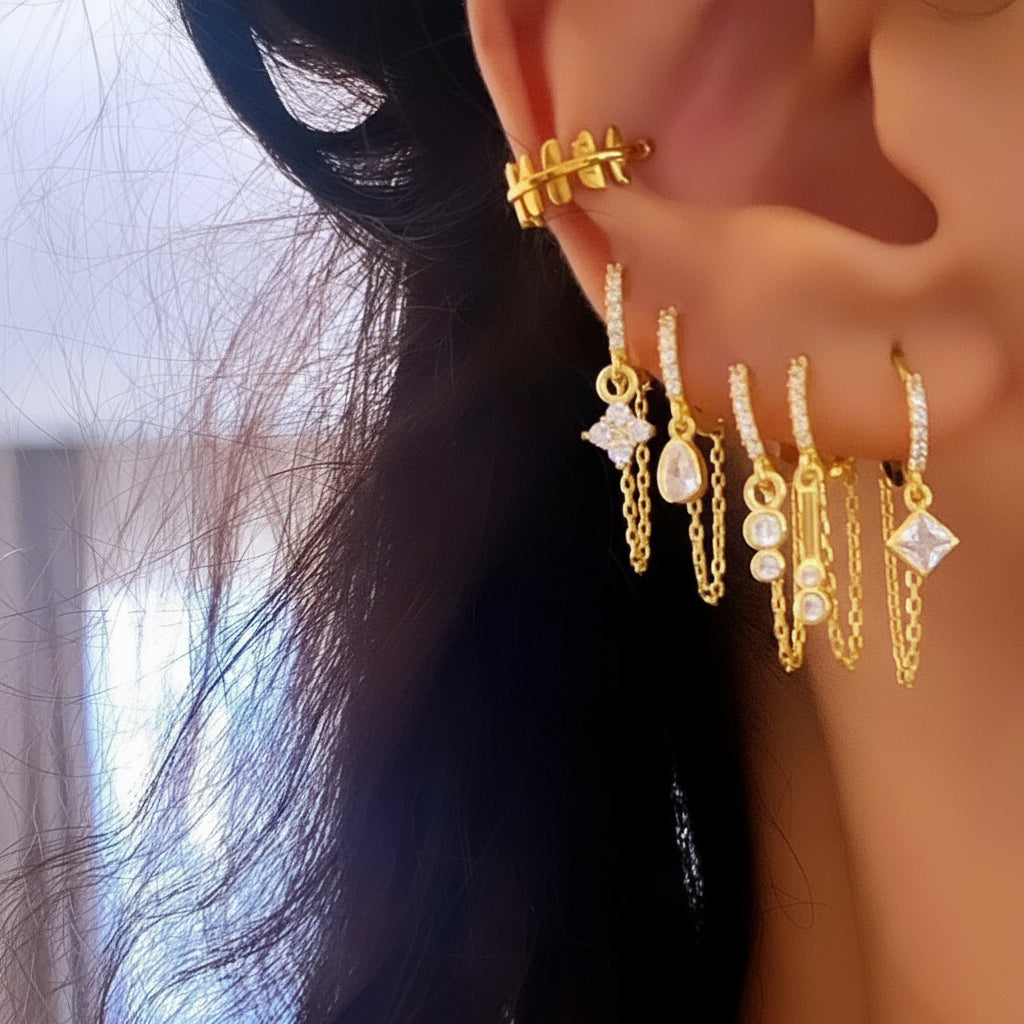 Gold earrings with various designs worn by a person